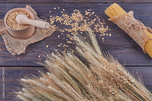 Top view wheat grains with mortar grinder and spaghetti on dark wood. photo