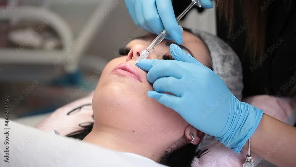 Lip augmentation. Beautician injects hyaluronic acid into the lips of a girl with a syringe. The cosmetologist doctor performs the procedure in the cosmetology office. Plastic surgery. Lip augmentation. Beautician injects hyaluronic acid into the lips of a girl with a syringe. The cosmetologist doctor performs the procedure in the cosmetology office. Plastic surgery.
