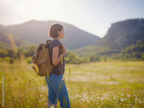 young woman with a backpack in a field at sunset