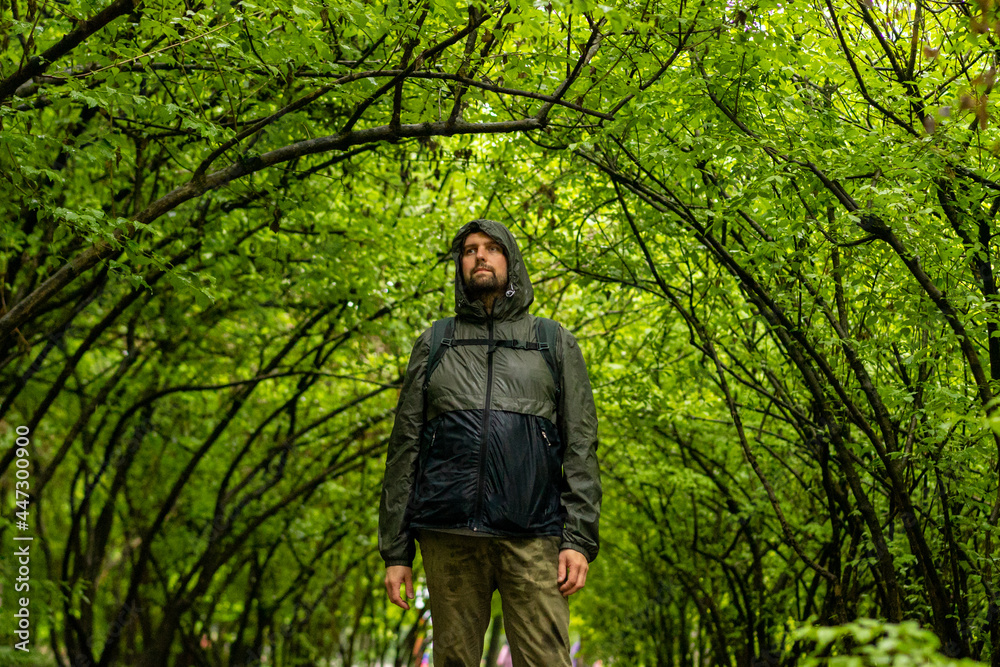 Man walking and relaxing in park. Tourist with backpack walking in park. Spending time alone in nature. Peaceful atmosphere. Front view. Man walking and relaxing in park. Tourist with backpack walking in park. Spending time alone in nature. Peaceful atmosphere. Front view.
