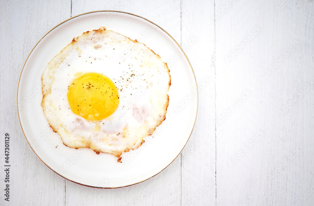 fried egg on a white plate on a wooden white table fried egg on a white plate on a wooden white table