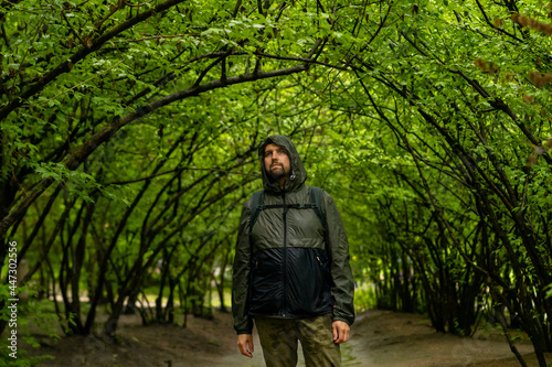 Man walking and relaxing in park. Tourist with backpack walking in park. Spending time alone in nature. Peaceful atmosphere. Front view.