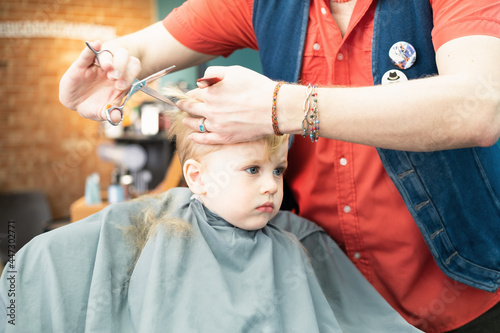 Cute little boy getting the first haircut in barbershop