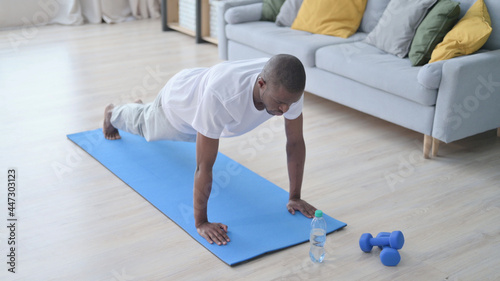 African Man doing Pushups on Yoga Mat at Home © stockbakers