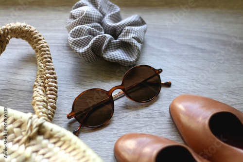 Straw bag, vintage shoes, sunglasses and scrunchie on wooden background. Selective focus.