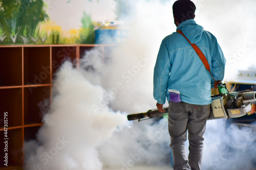 Workers spray mosquito pesticides with a motorized sprayer..