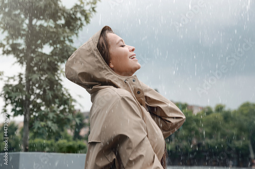 Woman with raincoat walking under rain in park