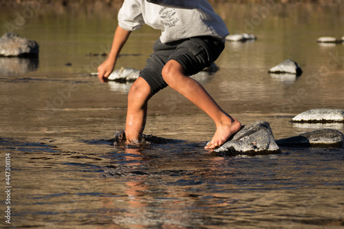 Child crossing a mountain river on stones in Santa Rosa de Calamuchita, Cordoba, Argentina photo