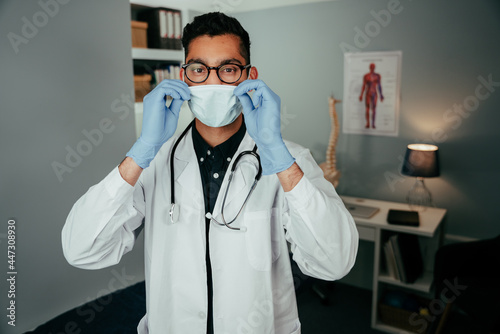 Mixed race male doctor working in office wearing surgical mask