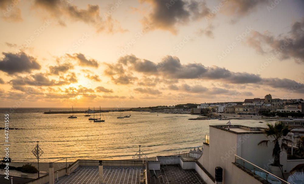 Beautiful sunrise in Otranto town bay, Apulia, Adriatic Sea, Salento, Italy. No people. Soft golden colors, cloudy sky. Summer morning in Italy.