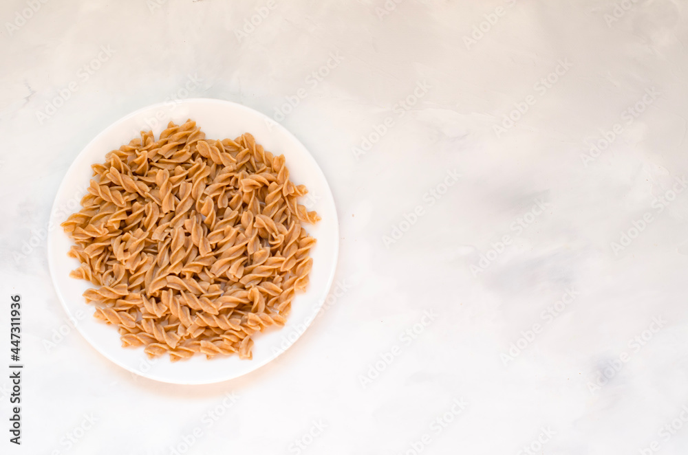Organic buckwheat Fusilli pasta in a white plate. Gluten Free Whole Grain Noodles. Healthy food concept. View from above. Flat lay. Copy space Organic buckwheat Fusilli pasta in a white plate. Gluten Free Whole Grain Noodles. Healthy food concept. View from above. Flat lay. Copy space