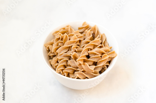 Organic buckwheat Fusilli pasta in a white bowl. Gluten Free Whole Grain Noodles. Healthy food concept. View from above. Flat lay. Copy space. Isolate