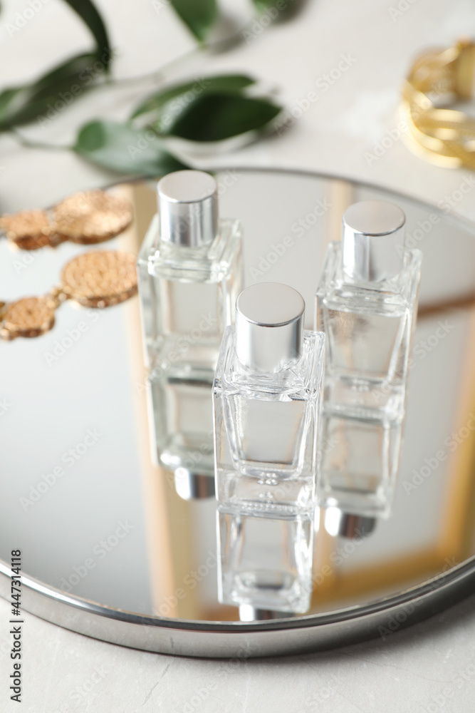Bottles of essential oil and mirror on light grey table, closeup Bottles of essential oil and mirror on light grey table, closeup