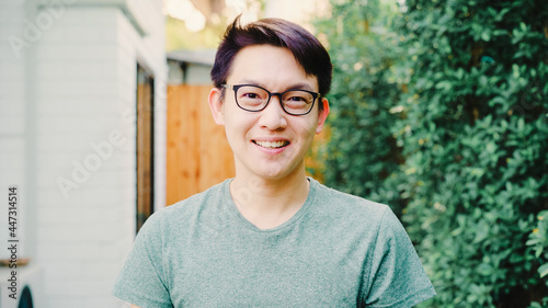 Portrait Asian Chinese man feeling happy smiling at house. Young friendly male relax toothy smile looking to camera while standing in the garden at home in the morning concept.