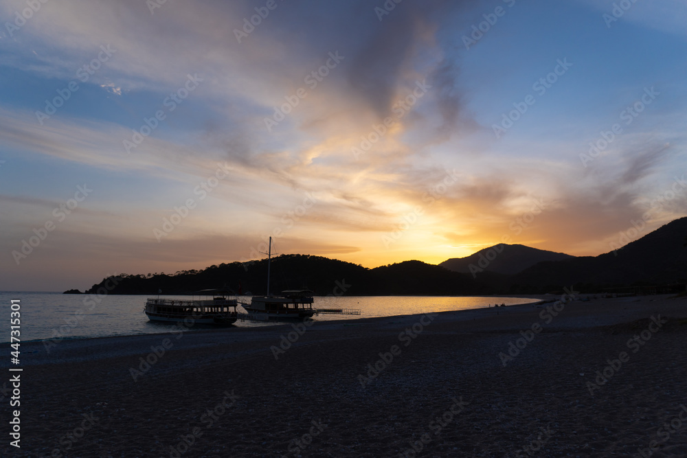 Golden hours. Sunset in the mountains near the sea. Moored boats at sunset. Sailboats on the empty seaside.