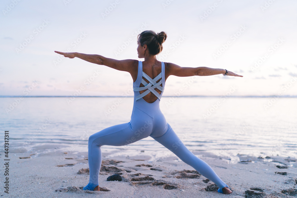 Young slender female performing yoga pose on seaside Young slender female performing yoga pose on seaside