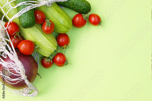 Ripe juicy red tomatoes  green cucumbers and zucchini in a string bag.