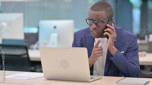 Angry Young African Businessman Talking on Phone in Office