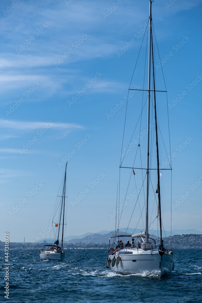 Sailing boats with open white sails, blue sky and rippled sea background