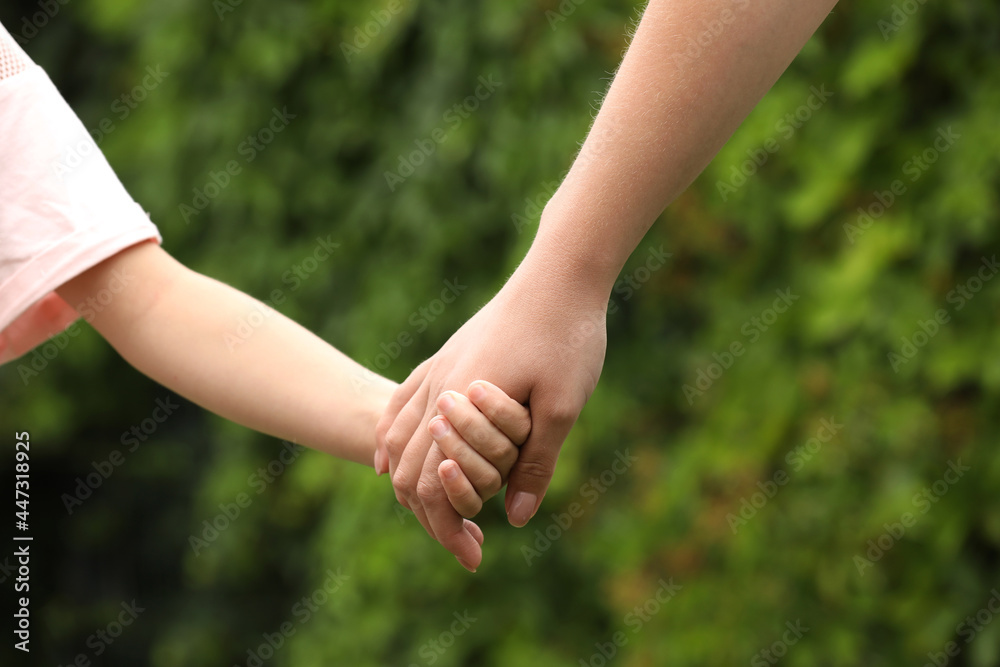 Woman and child holding hands outdoors, closeup Woman and child holding hands outdoors, closeup