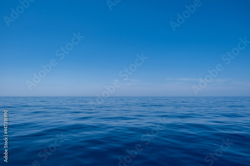 Sea water surface calm with small ripples, deep blue color and blue sky background, © Rawf8