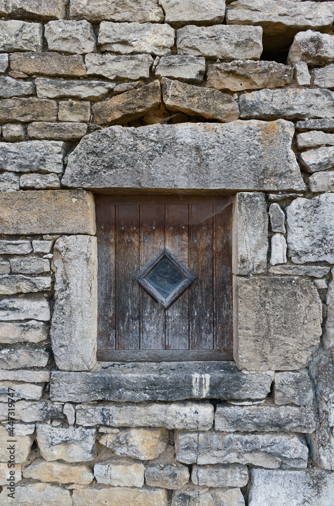 old stone wall with vintage shutter and tiny window