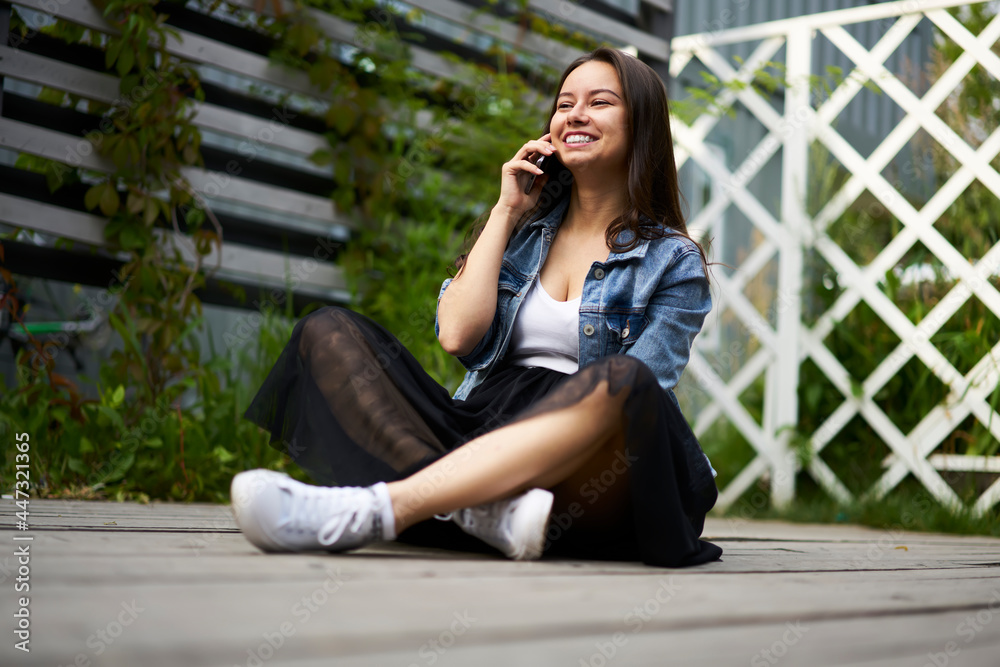 Funny hipster girl in trendy apparel enjoying positive friendly conversation via modern smartphone device, happy female connecting to roaming for making international cellular conversation