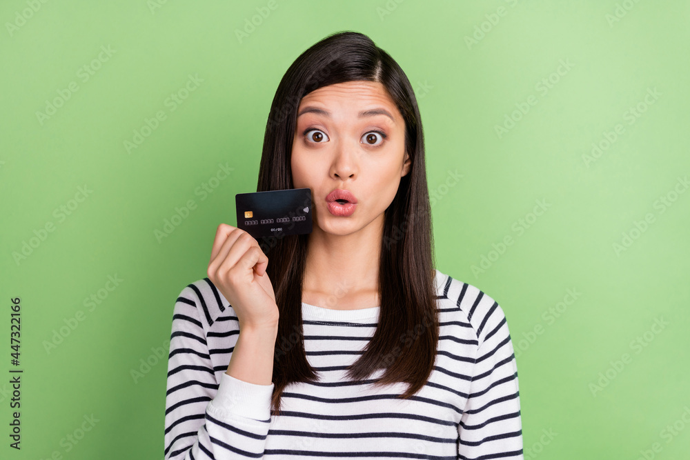 Fototapeta premium Portrait of attractive amazed funky girl holding in hands bank card staring pout lips news isolated over green color background