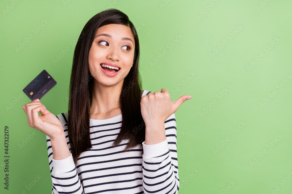 Portrait of attractive trendy cheerful girl holding in hands bank card showing copy service isolated over green color background Portrait of attractive trendy cheerful girl holding in hands bank card showing copy service isolated over green color background