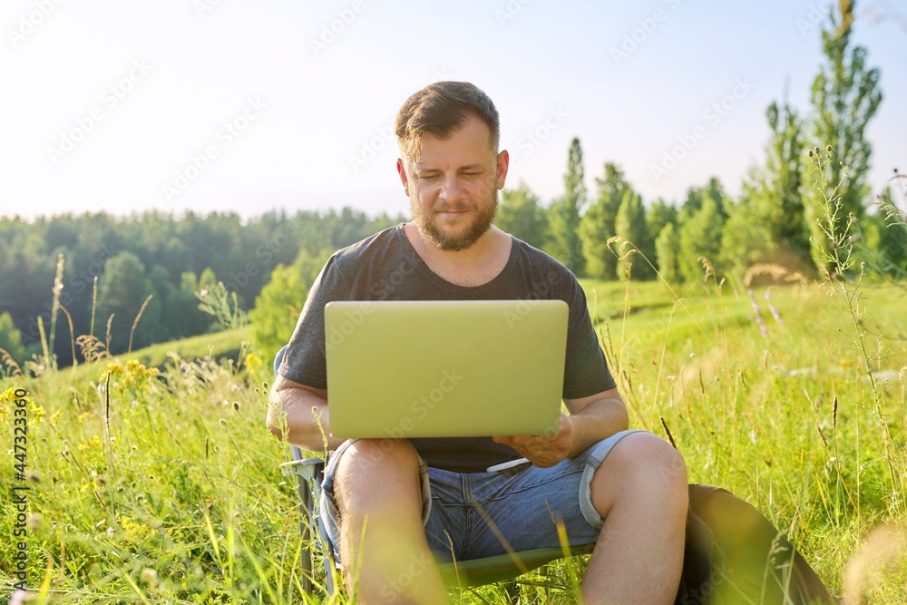 Middle-aged man with backpacks with laptop in nature Middle-aged man with backpacks with laptop in nature