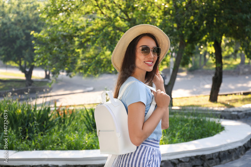 Beautiful young woman with stylish backpack in city park