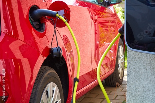 Ein rotes Elektroauto wird über ein Kabel aufgeladen.