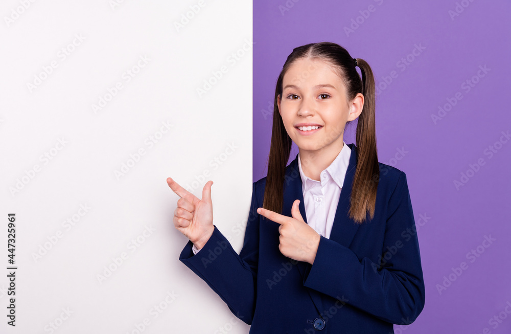Photo of pretty adorable schoolgirl dressed blue uniform pointing fingers white placard empty space isolated violet color background Photo of pretty adorable schoolgirl dressed blue uniform pointing fingers white placard empty space isolated violet color background