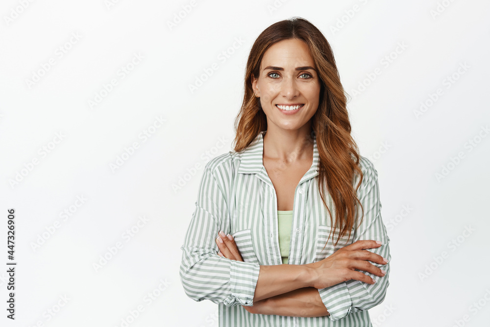 Ambitious and confident business woman, female entrepreneur standing with arms crossed and smiling self-assured at camera, saleswoman against white background Ambitious and confident business woman, female entrepreneur standing with arms crossed and smiling self-assured at camera, saleswoman against white background