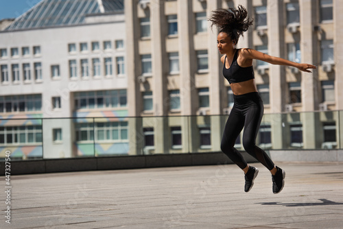 African american sportswoman jumping on urban street