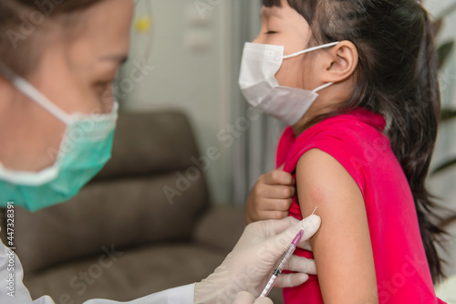 Asian doctor injection vaccine for protecting virus covid-19 to a girl wear medical mask People are Girls are vaccinated against influenza every year.
