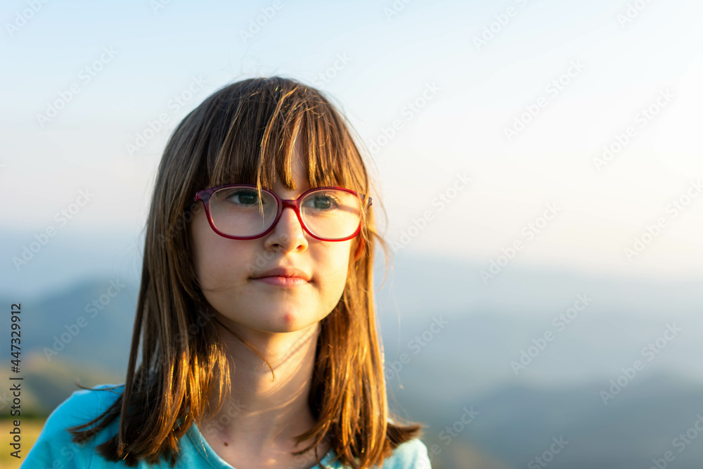Smiling girl 8 year old posing over mountain background. Looking at camera. Summer season.