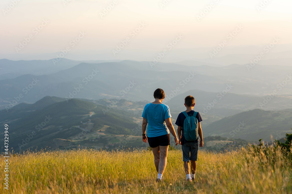 Happy Mother and son  having fun in outdoor hike in mountains at sunset. Weekend travel in mountains. Mother and son stands against mountains sunset. Travel tourism adventures concept