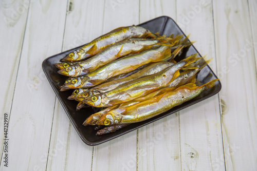 Capelin (Latin Mallotus villosus) is cold smoked on a black rectangular plate. Food is a delicacy snack for beer. photo