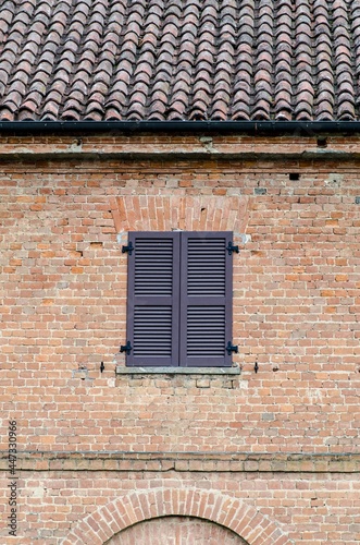 Architecture, typical exposed brick facade with window closed by elements from shutters, rustic building loved for its elegance and simplicity