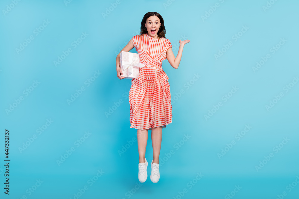 Photo of amazed lady jump hold present open mouth omg reaction wear striped dress shoes isolated blue color background Photo of amazed lady jump hold present open mouth omg reaction wear striped dress shoes isolated blue color background