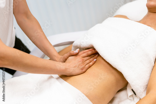 Middle-aged woman having a belly massage in a beauty salon.