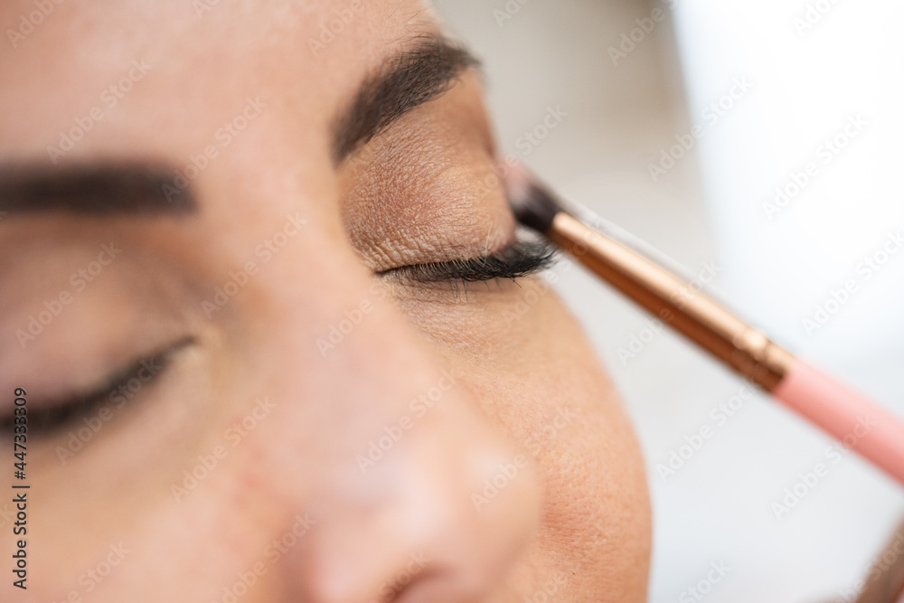 Close-up of a make-up artist applying eye shadow to her client.