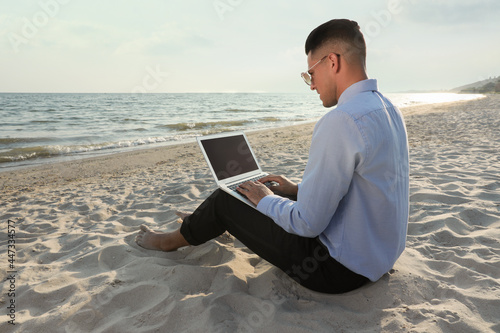 Businessman working with laptop on beach. Business trip