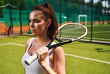 Pensive young athlete standing on the tennis court