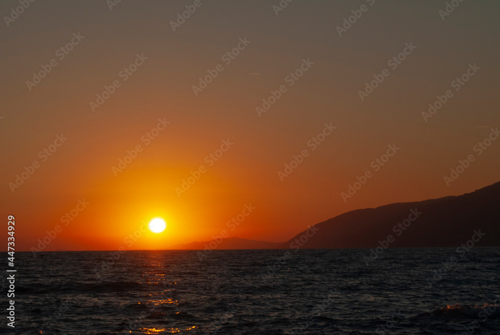 Sunset over the sea and mountains in Abkhazia. Picturesque seaside landscape in the evening.