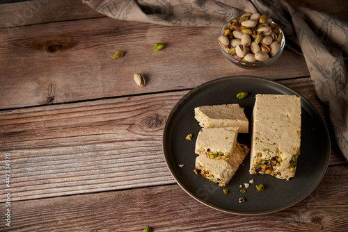 Organic halva with pistachios on a wooden surface. Traditional middle eastern sweets. Jewish, turkish, arabic oriental national dessert. Turkish delight concept. Natural vegan product. Copy space. photo