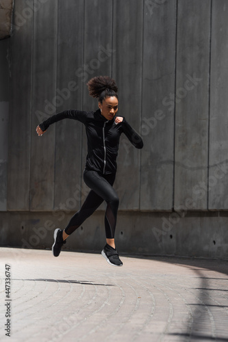 African american runner in black sportswear running outdoors