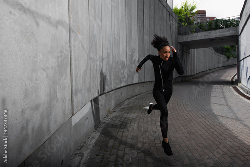 Focused african american sportswoman training while running outdoors