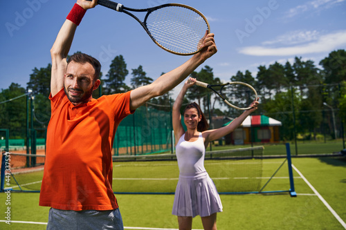 Two players performing a warm-up exercise with rackets raised overhead © Viacheslav Yakobchuk